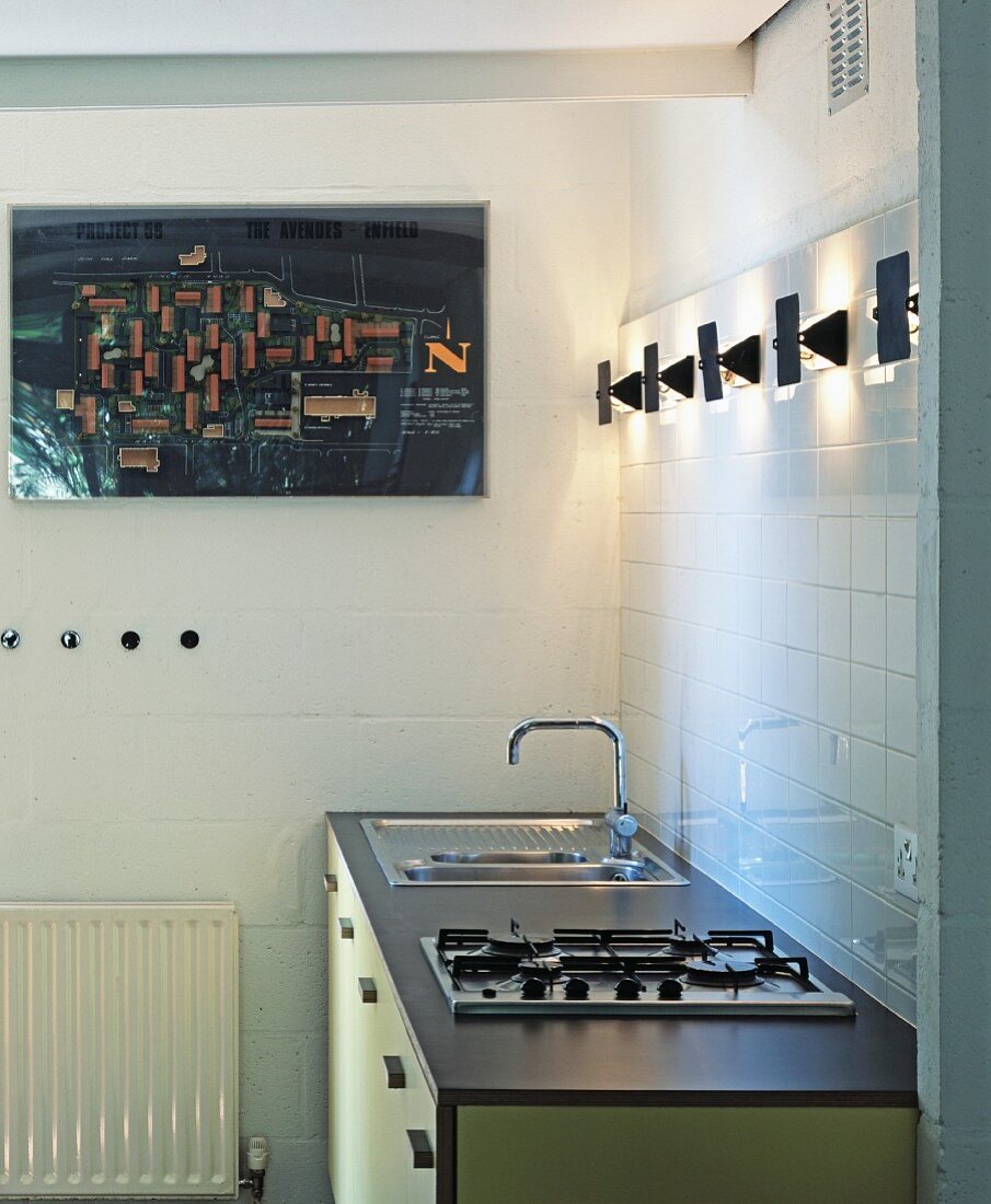 Einfache Küchenzeile in Pastellgelb und Grau mit modernen Wandlämpchen und Luftbildfoto