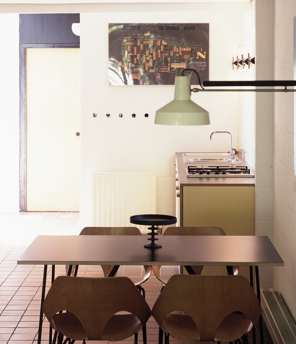 Essplatz mit Holz-Schalensitzen und Wandlampe im Industriestil vor gradliniger Küchenzeile