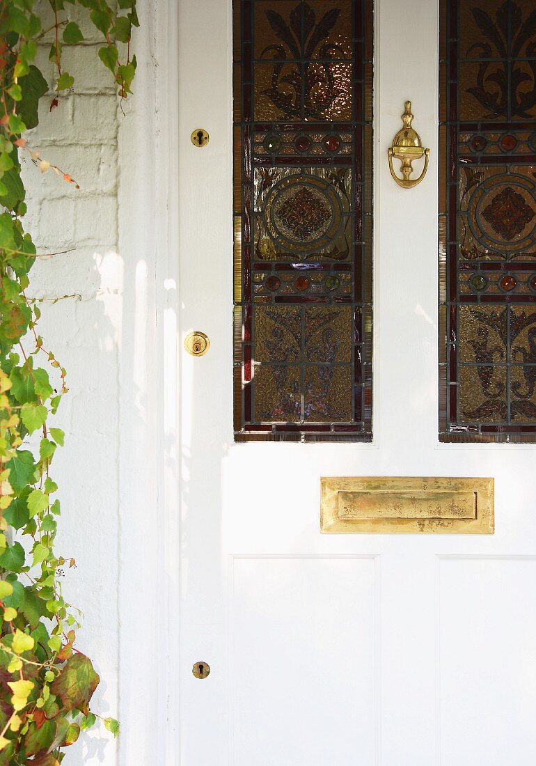 White, antique front door with stained glass windows and brass letterbox