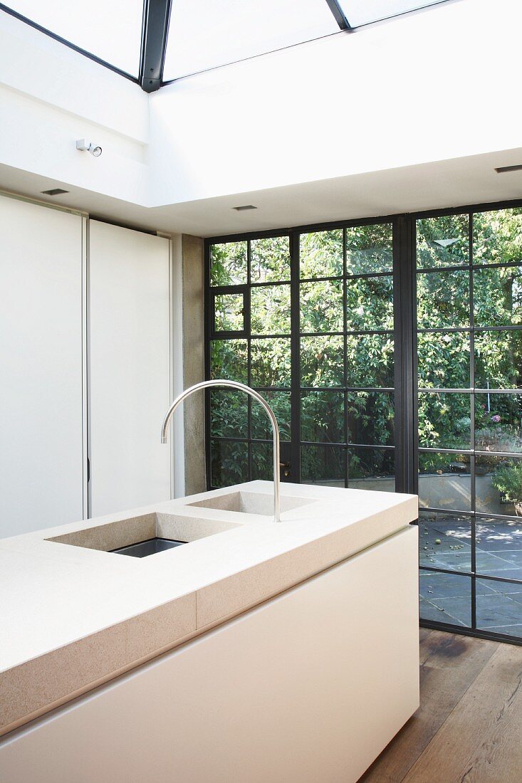 Moderner Küchenblock mit massiver Steinplatte vor historischer, metallgerahmter Fensterfront