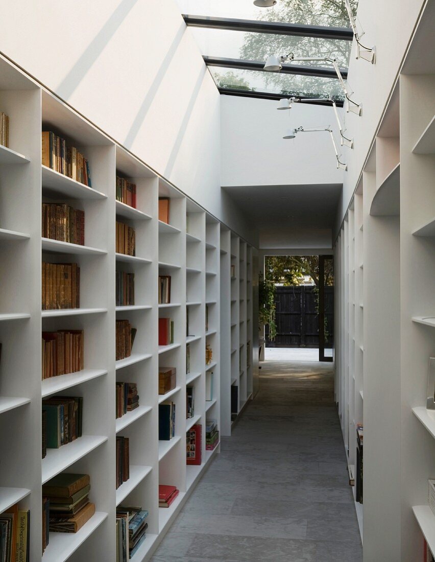 Bibliotheksgang mit schrägem Oberlicht und Fenstertür zu Innenhof