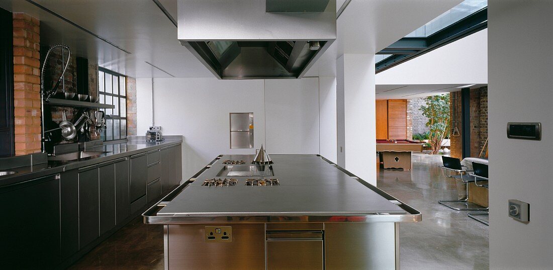 A spacious stainless steel kitchen leading onto a loft-style living room-cum-dining room