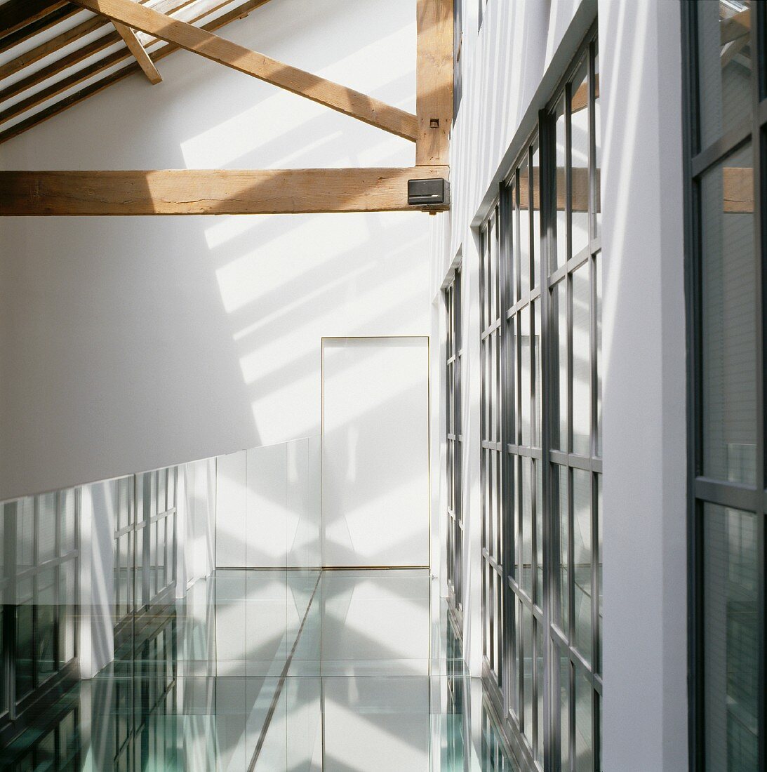 Kühle Lichtreflexionen auf Galerie unter offener Dachkonstruktion aus Holz