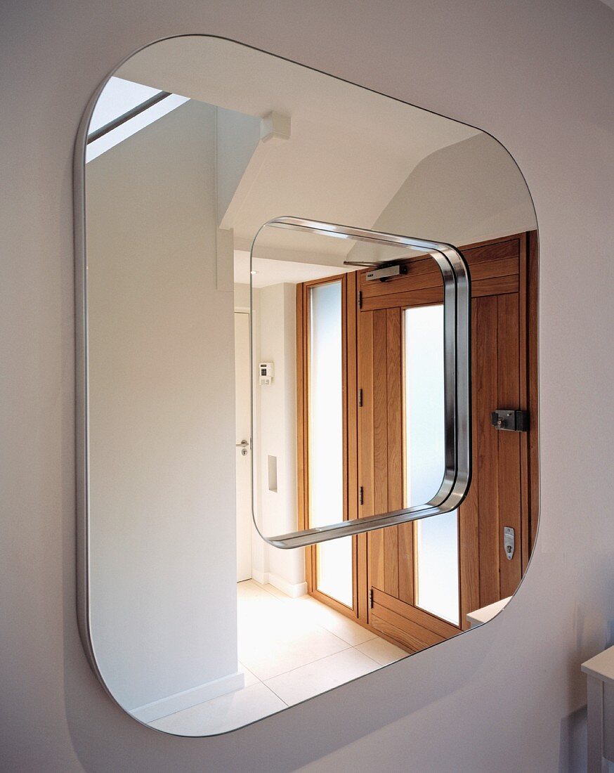 Square mirror with rounded corners reflecting front door
