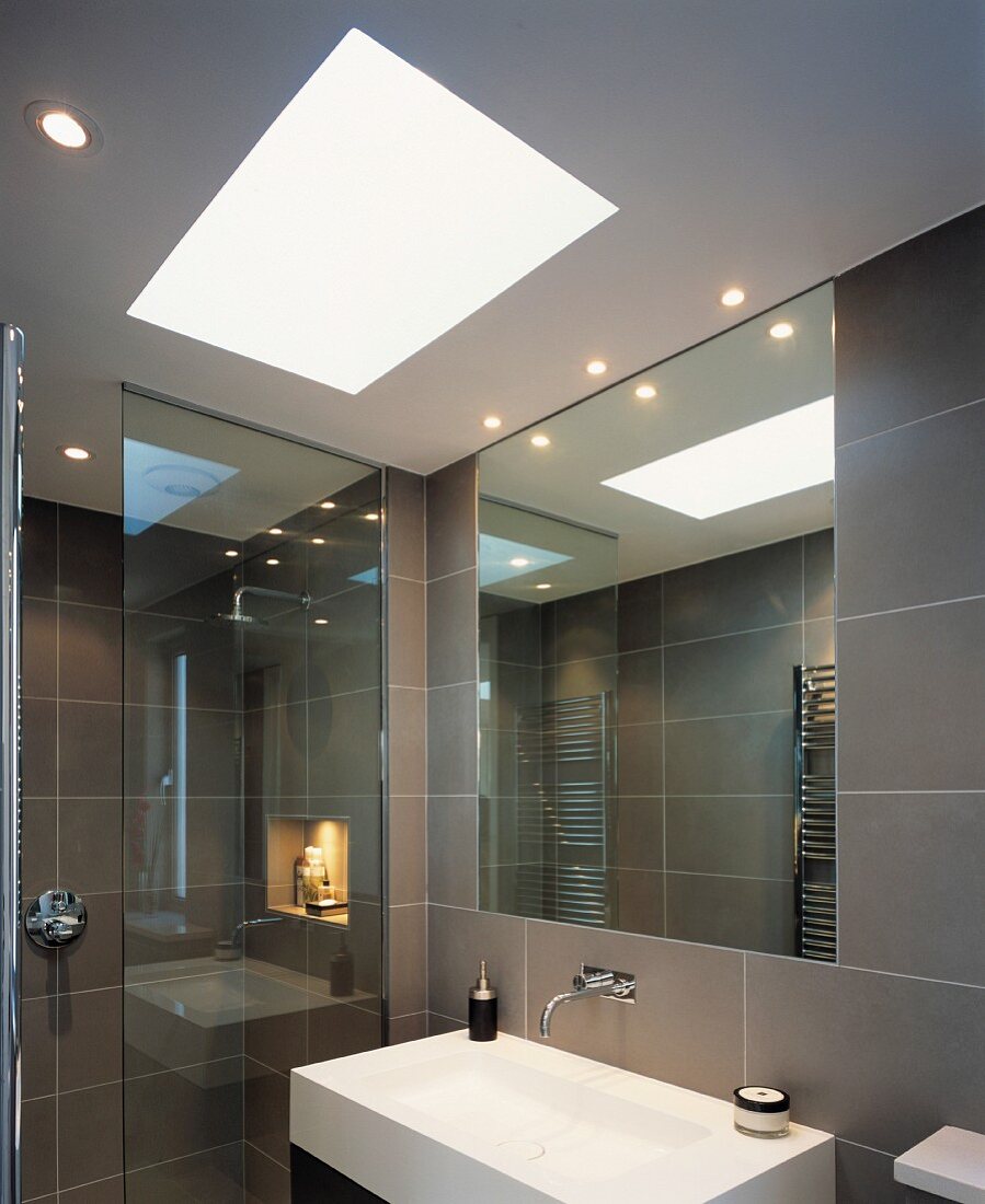 Modern, grey-tiles bathroom with skylight above designer sink