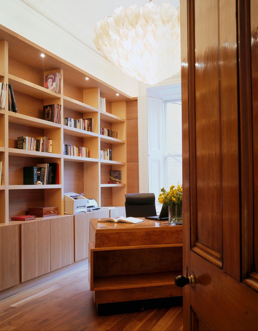 Blick durch offene Tür auf Wandbücherregal aus Holz im Wohnzimmer