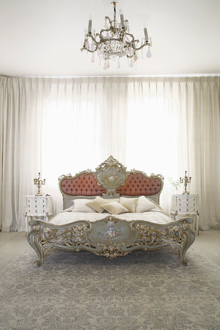 Rococo-style double bed in front of closed curtains in bedroom