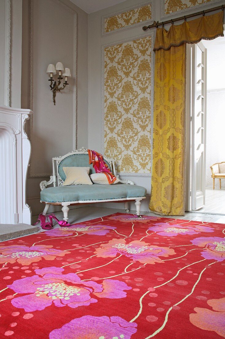 Farbenkräftiges Blumenmuster auf Teppich vor Sitzbank im Rokokostil