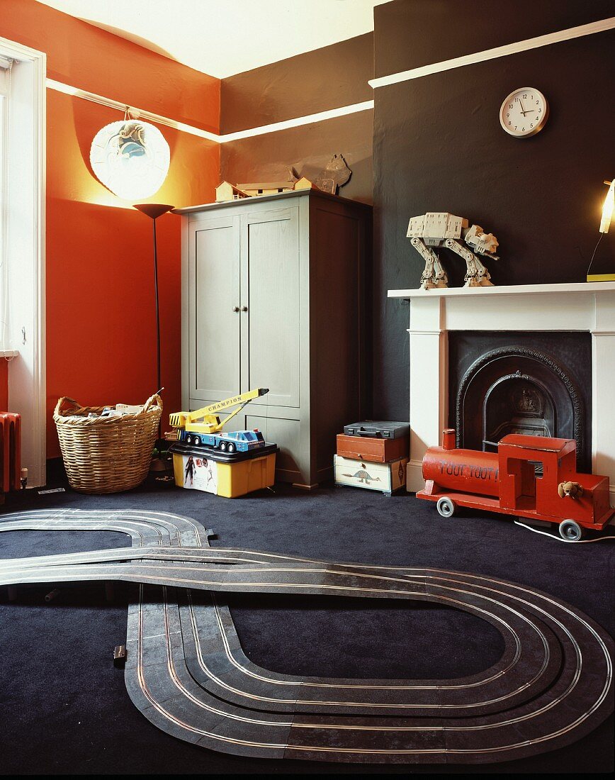 Toy racetrack on black carpet and coloured walls in child's bedroom