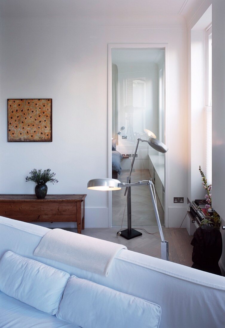 Standard lamps in corner of room in front of glass door with view into bedroom
