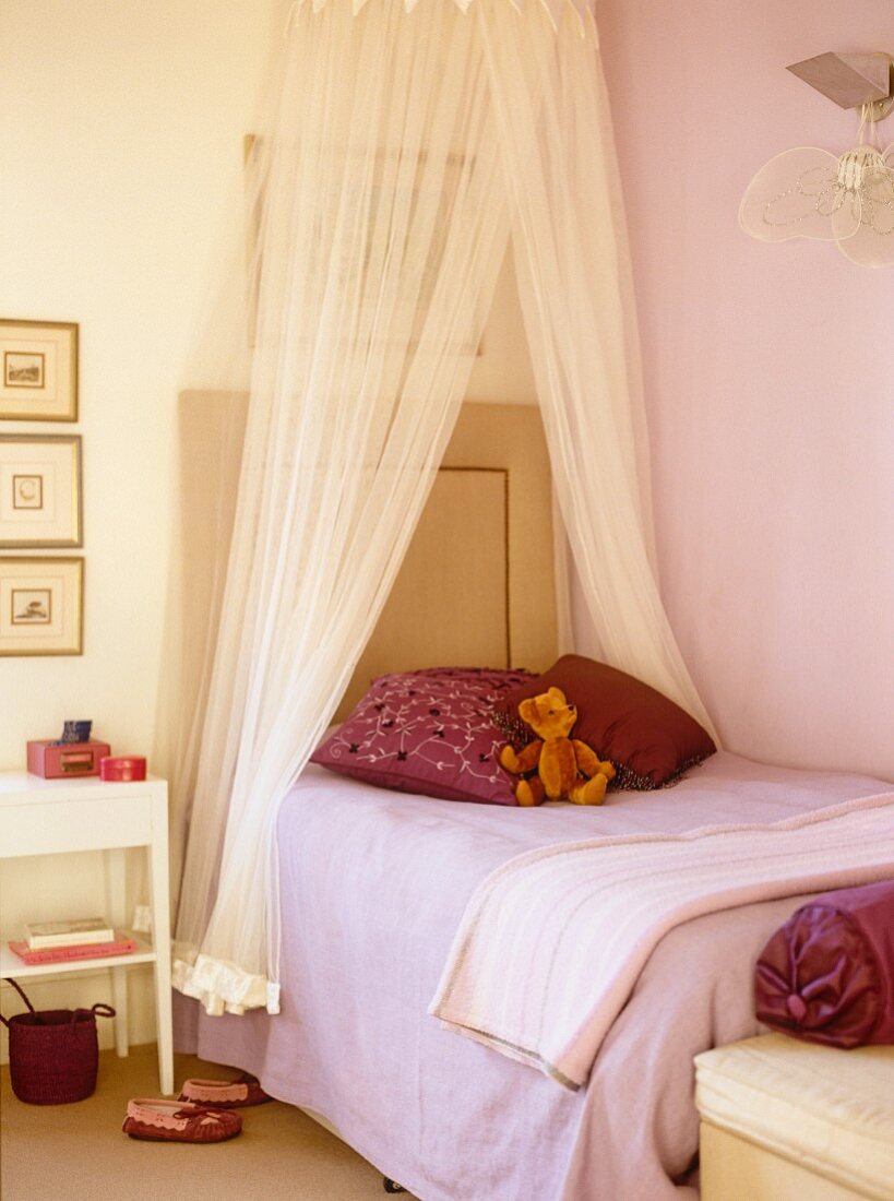 Pink girl's bedroom with canopy bed and teddy bear