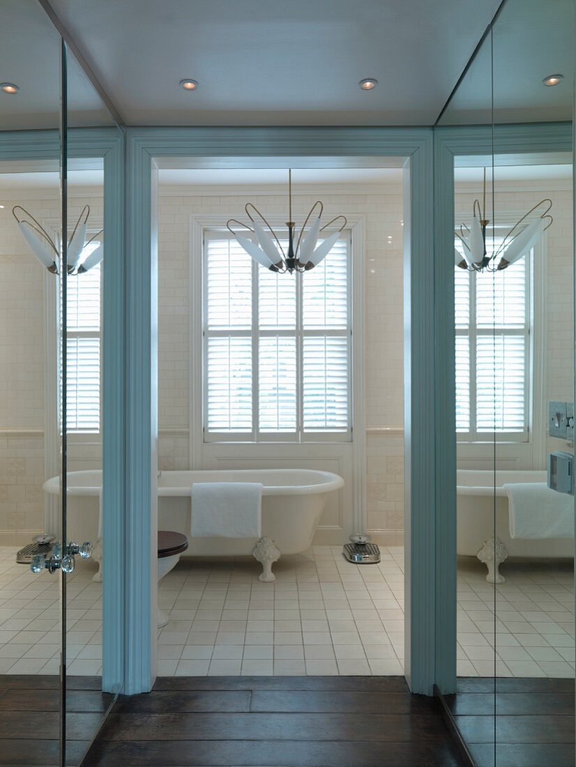 Corridor with mirrored cupboard doors and view of vintage-style bathtub through open door