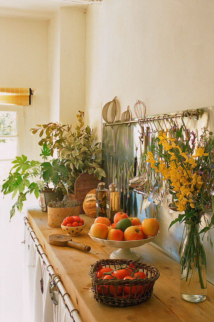Kitchen counter with fruit bowl, plants and flowers in natural light