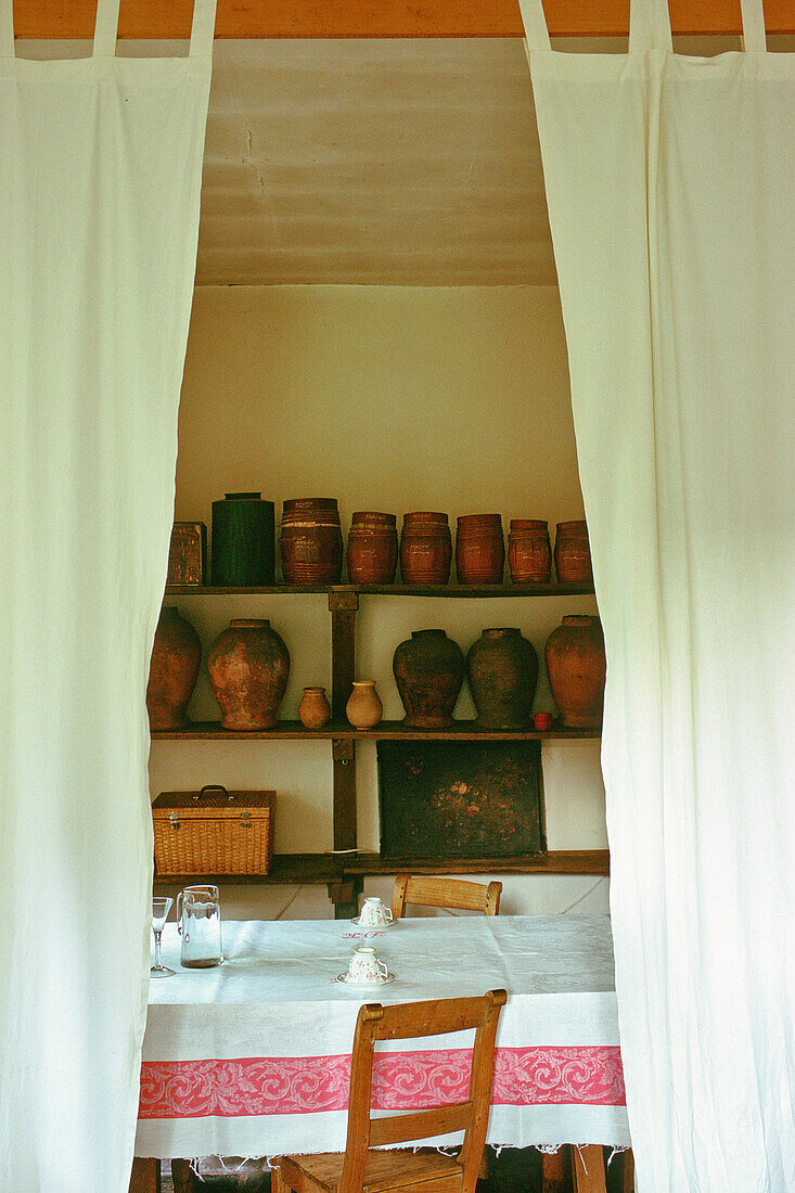 Dining table with tablecloth and rustic clay pots in the background