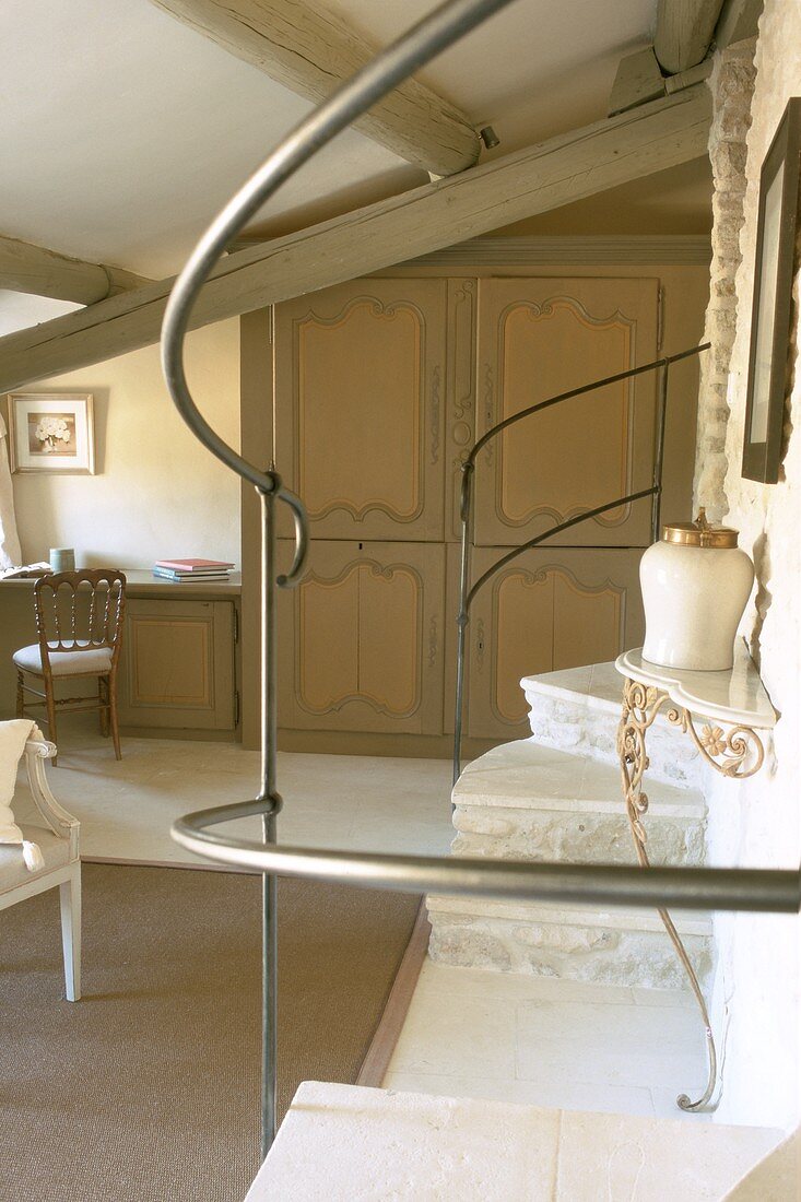 View of stone staircase with marble treads and wall console through metal balustrade