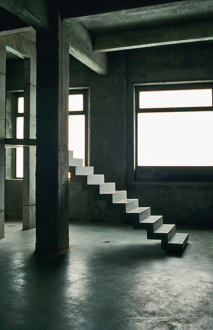 Free-floating staircase in a minimalist room with concrete walls