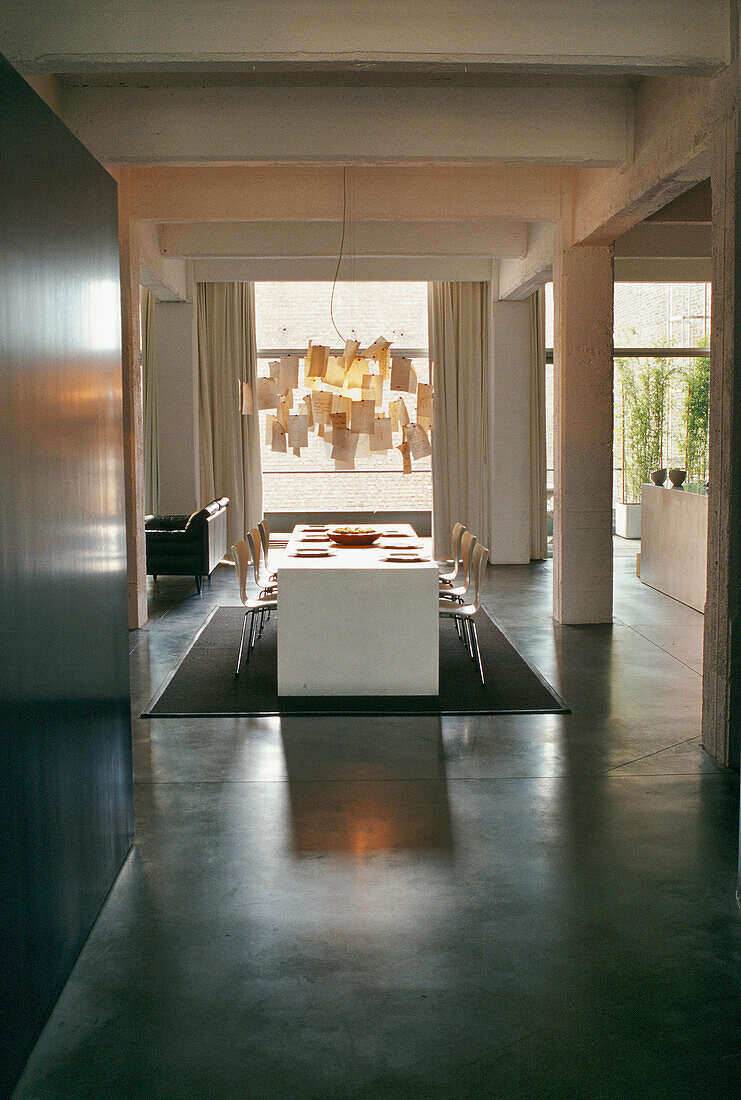 Essbereich mit langem Tisch und moderner Pendelleuchte in Loft-Apartment