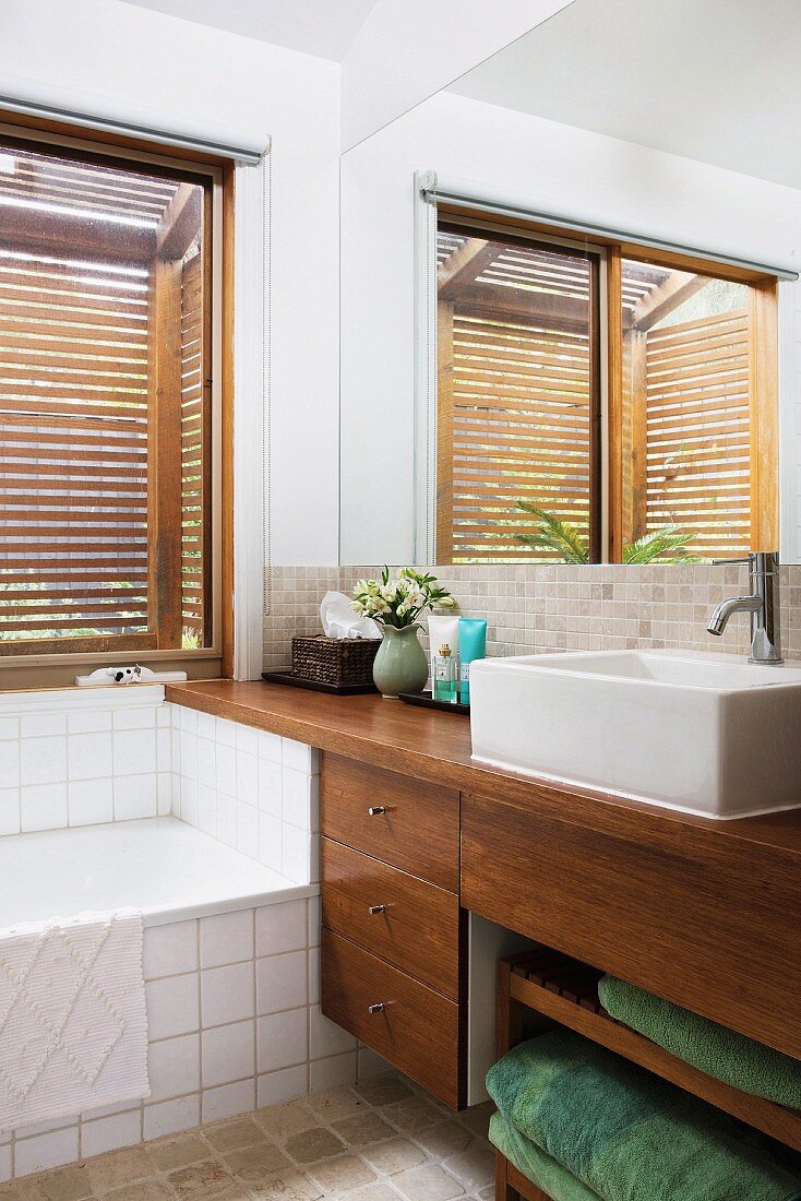 Badezimmerecke mit eingebauter Badewanne und modernem Waschtisch mit Unterschrank aus Holz