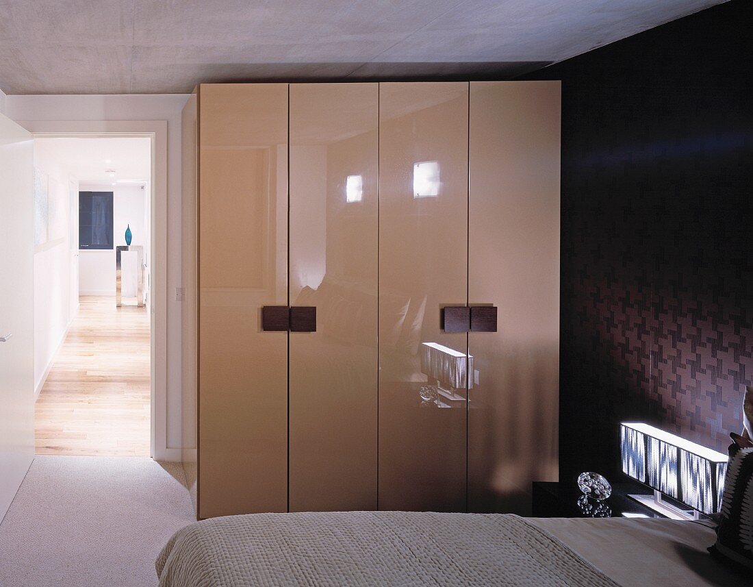 Wardrobe with glossy doors in bedroom and open door with view of hallway
