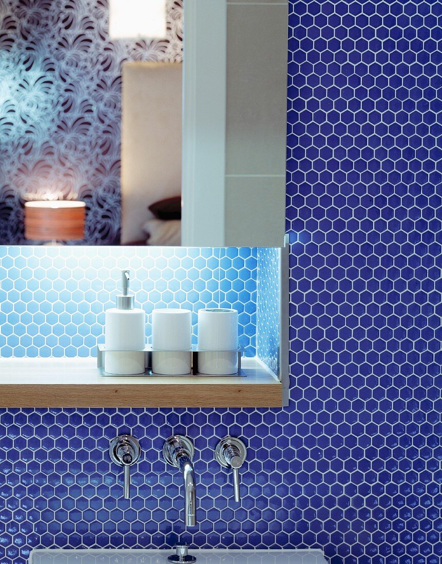 Spiegelschrank mit indirekter Beleuchtung und Ablage vor blauer Mosaikfliesenwand