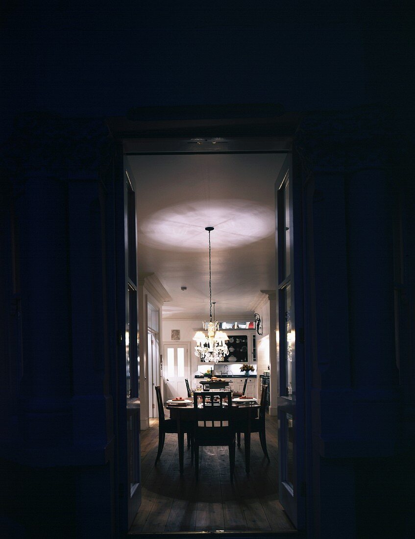 View of illuminated dining table through open double doors