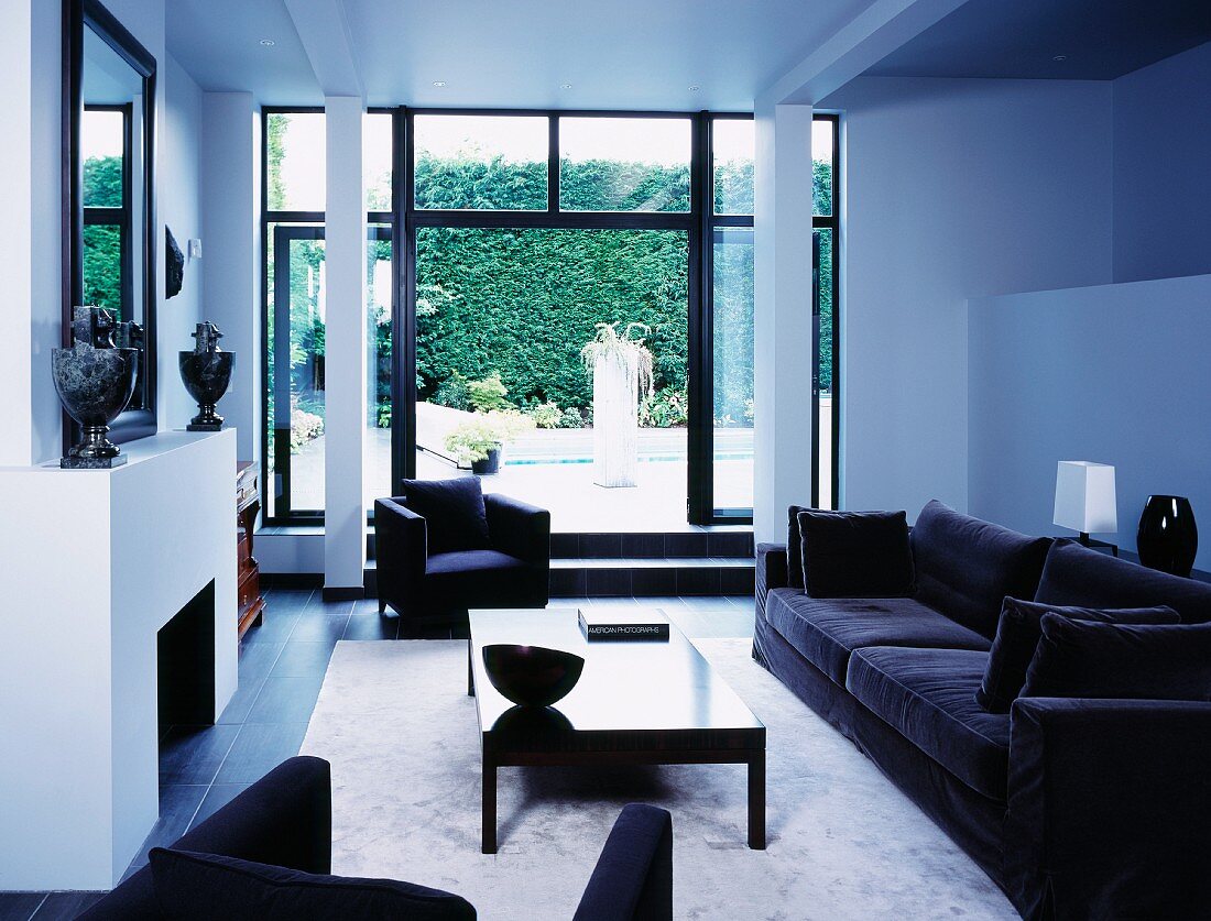 Black sofa set in white, modern living room with view of terrace
