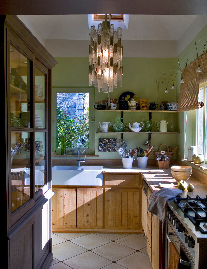 Country-style wooden kitchen with hanging lamp and green walls