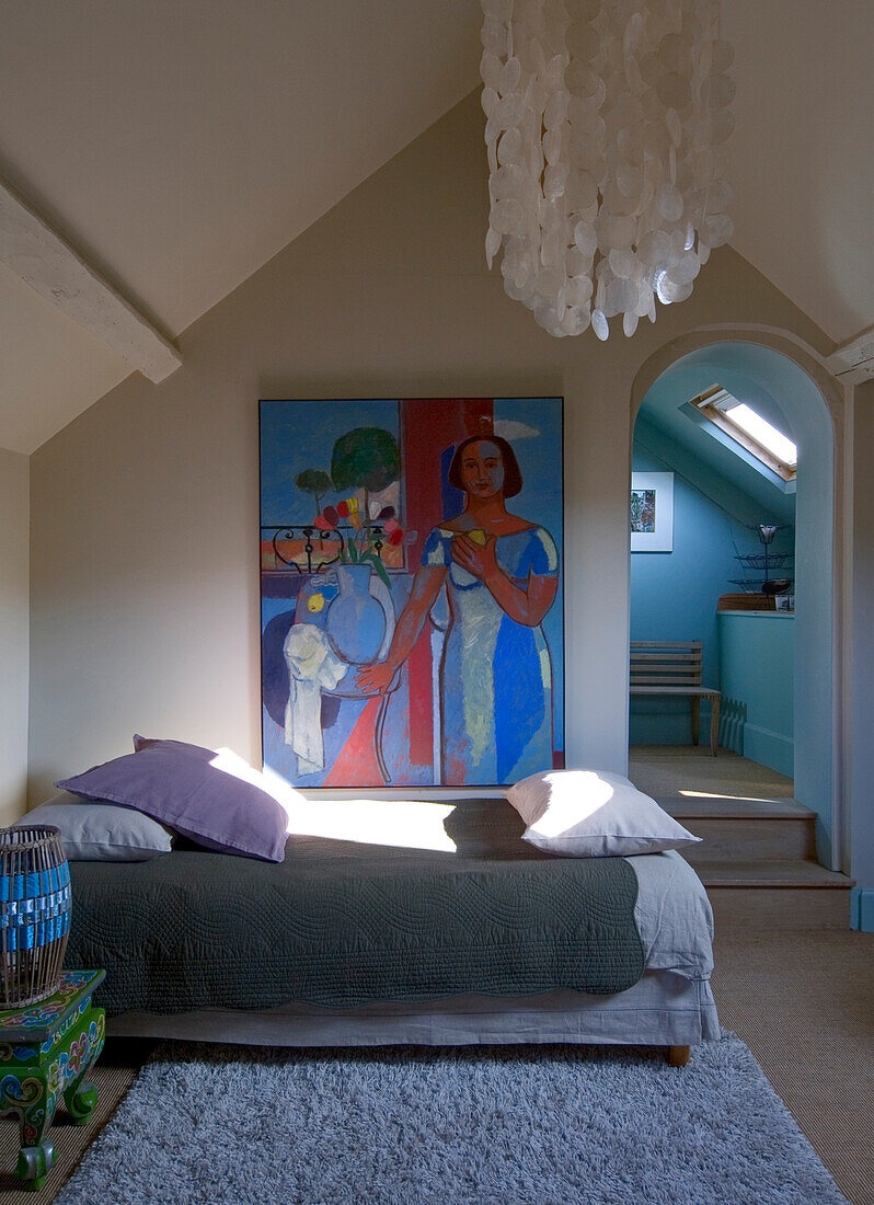 Sloping ceiling bedroom with artwork and large ceiling lamp