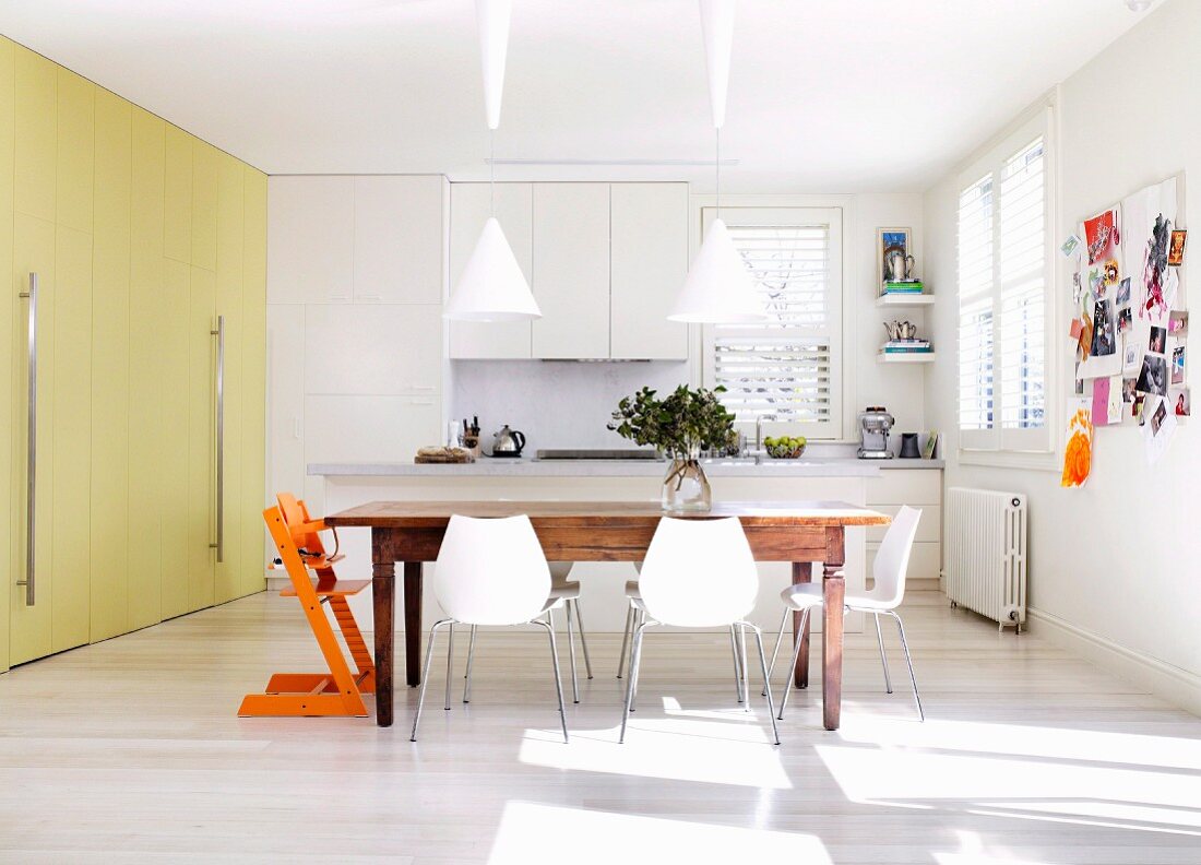 weiße Stühle am rustikalen Holztisch in moderner Küche