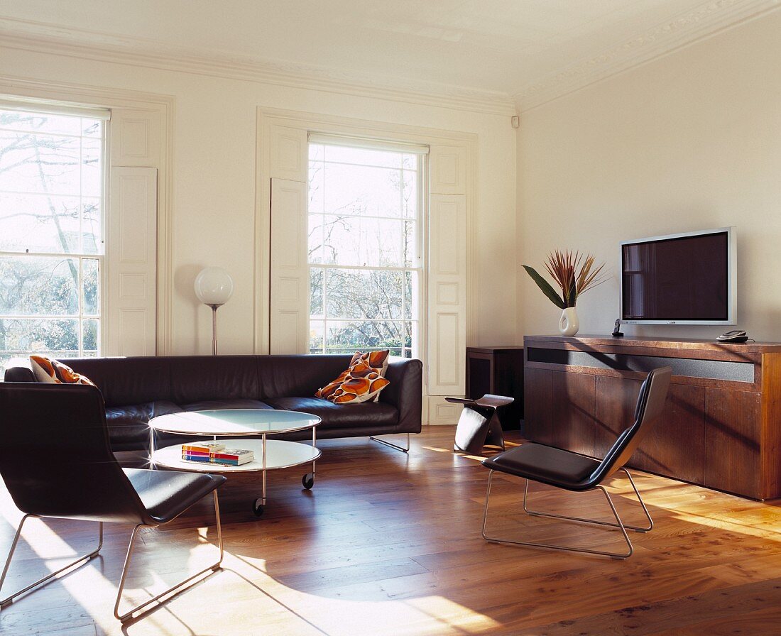 Sessel und Couch aus schwarzem Leder im Retrostil im Wohnraum mit klassischem Flair