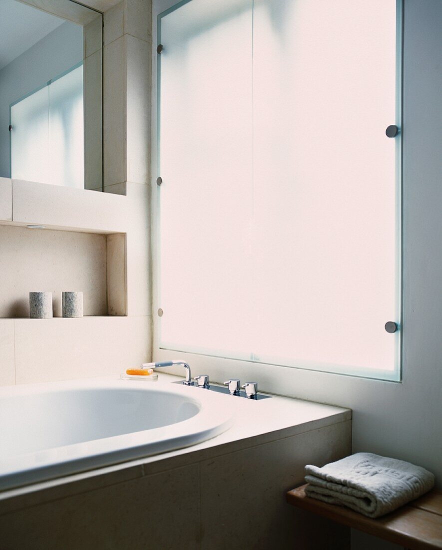 Bathtub in front of frosted glass window