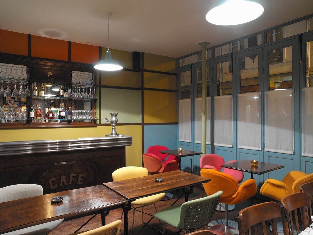 Bar im Retrostil mit farbig gepolsterten Schalenstühlen und farbigen Wandelementen