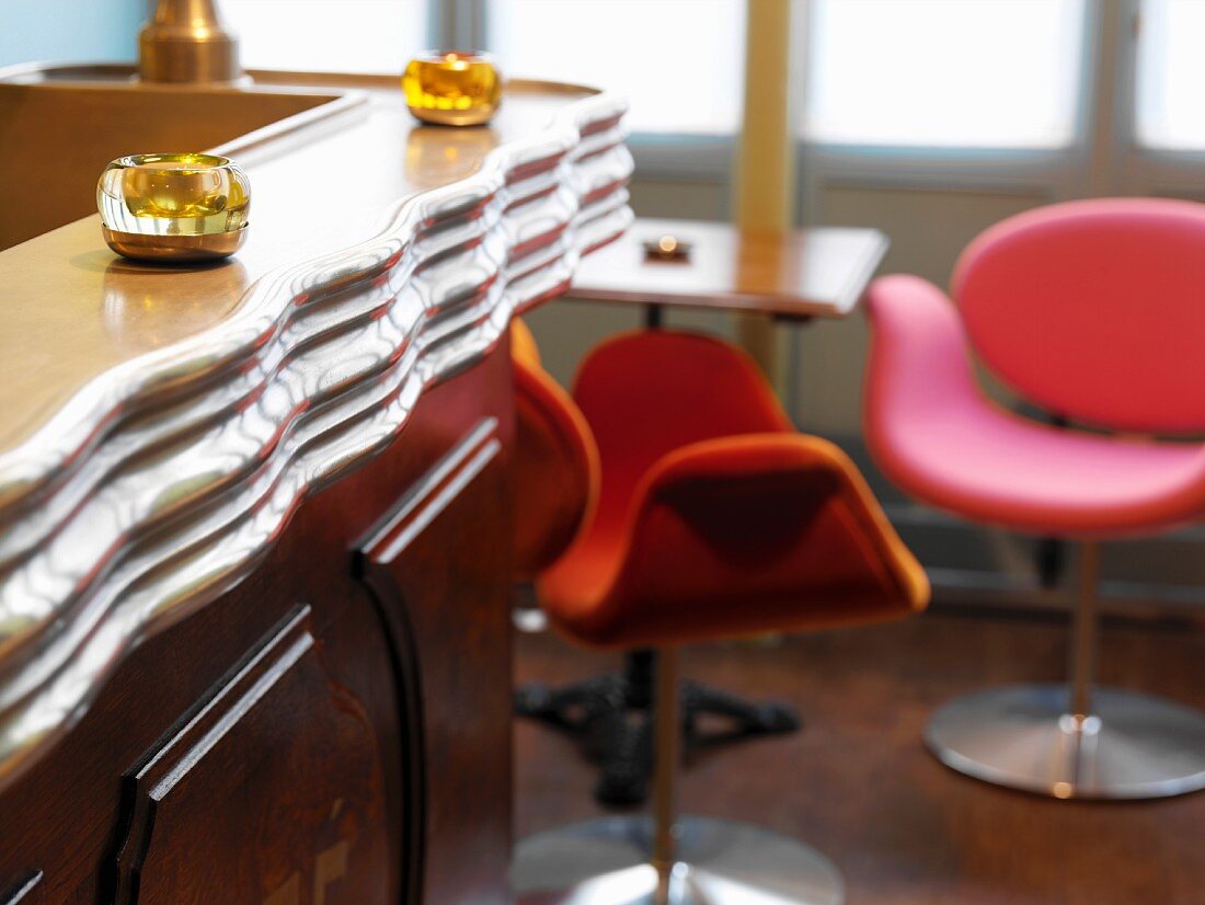 Hotelbar im Retrostil mit Schalensitzen in peppigen Farben am kleinen Tisch