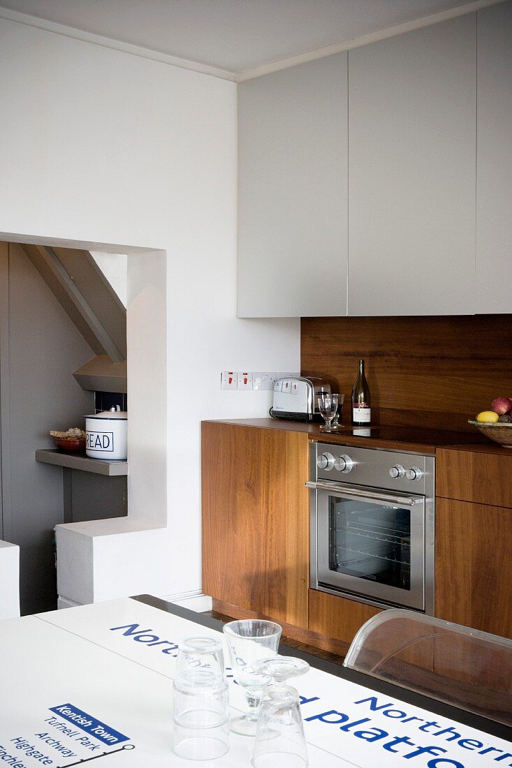 Modern kitchen unit in fine wood with white suspended cupboards and table top with printed underground map