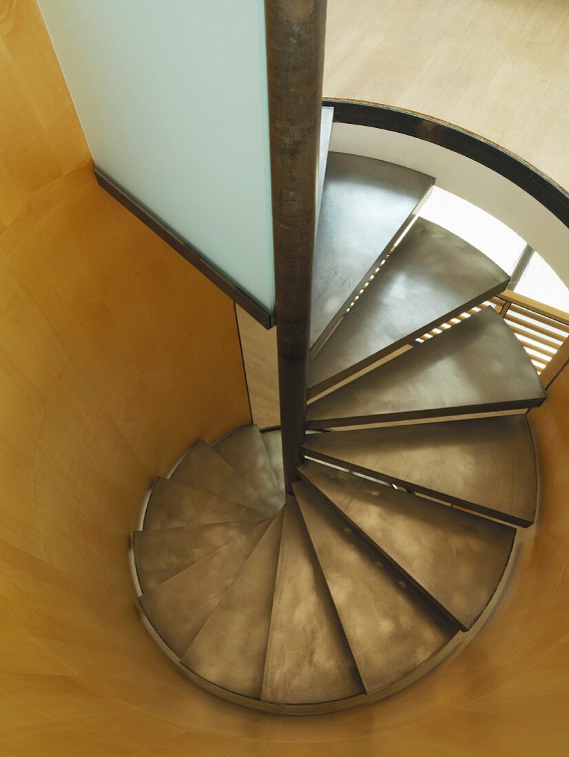 Exquisite, contemporary spiral staircase with metal treads in wood-panelled, cylindrical stairwell