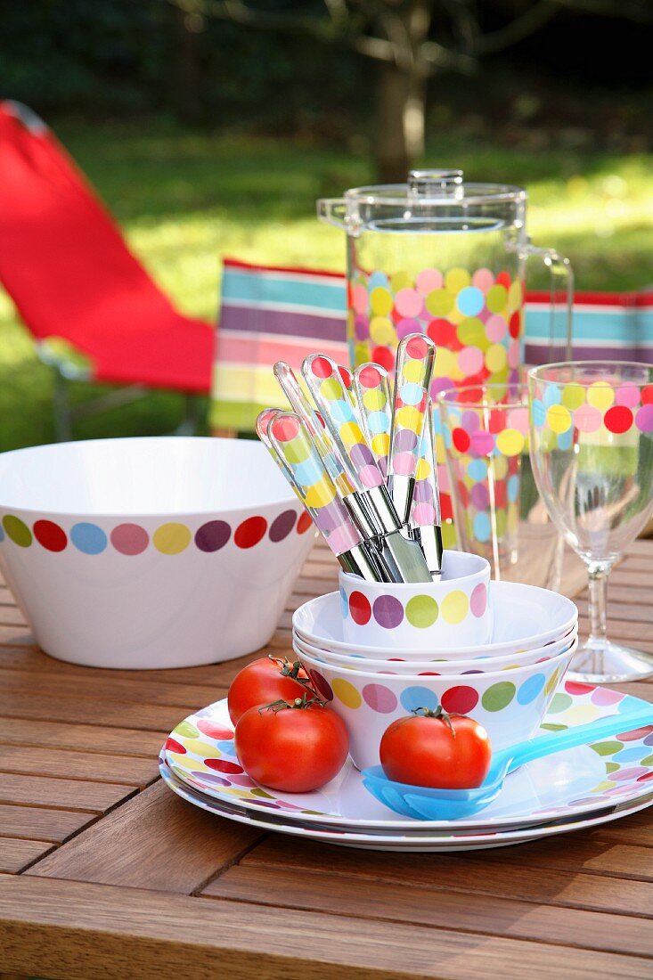 Gepunktetes farbenfrohes Geschirr & Besteck auf Tisch im Freien