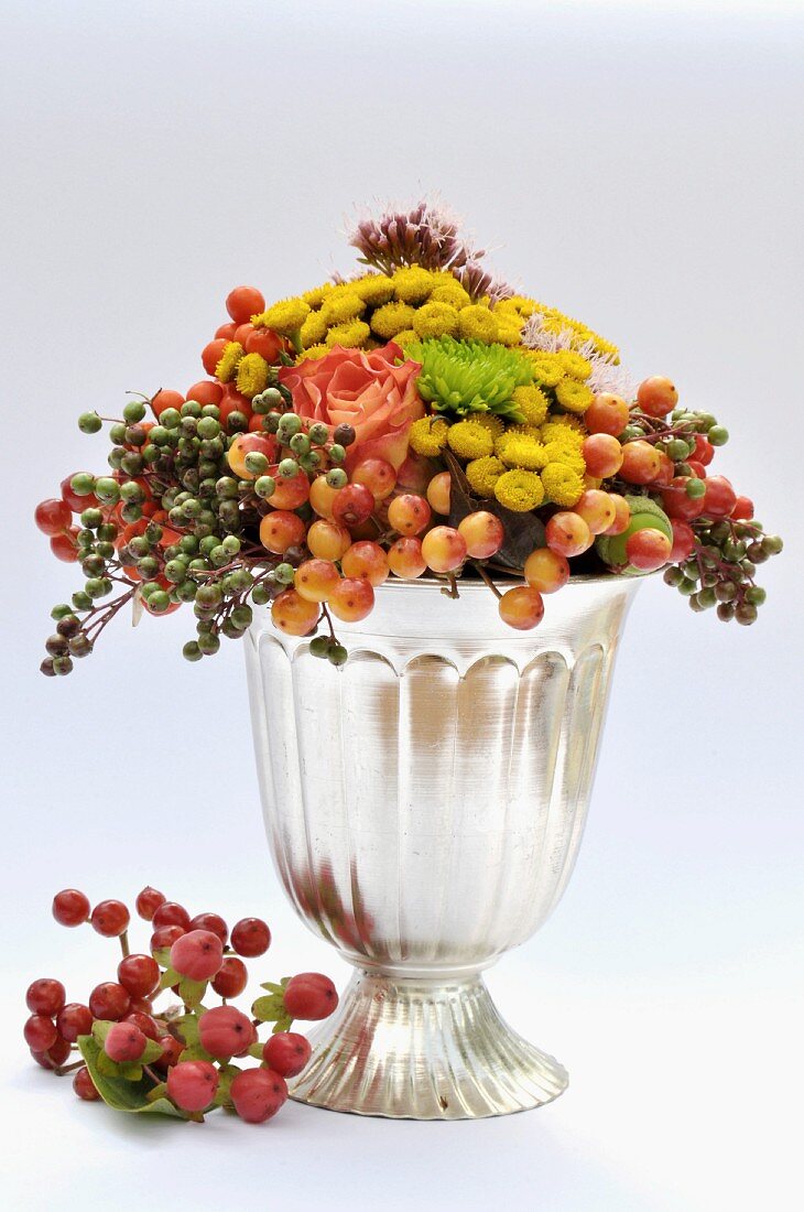 Autumnal arrangement of flowers & berries in silver vase