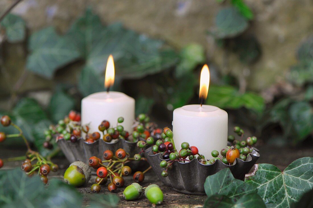 Candles in metal tart cases decorated with autumnal berries & acorns