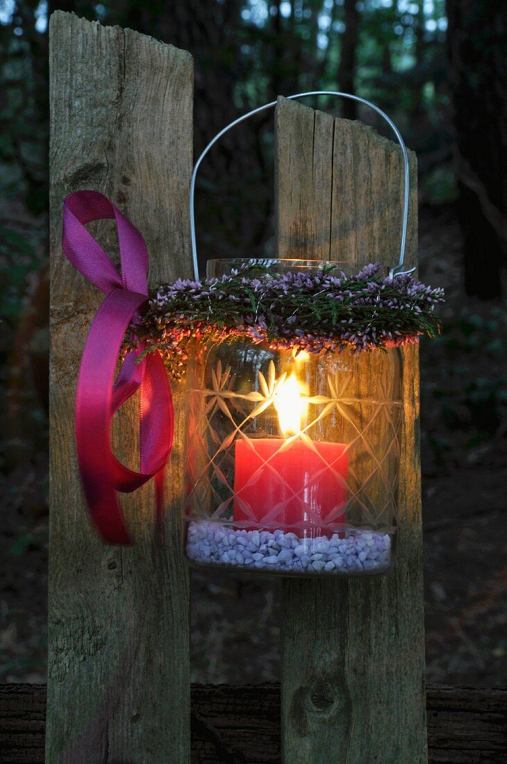 Storm lamp with wreath of heather hanging on wooden fence