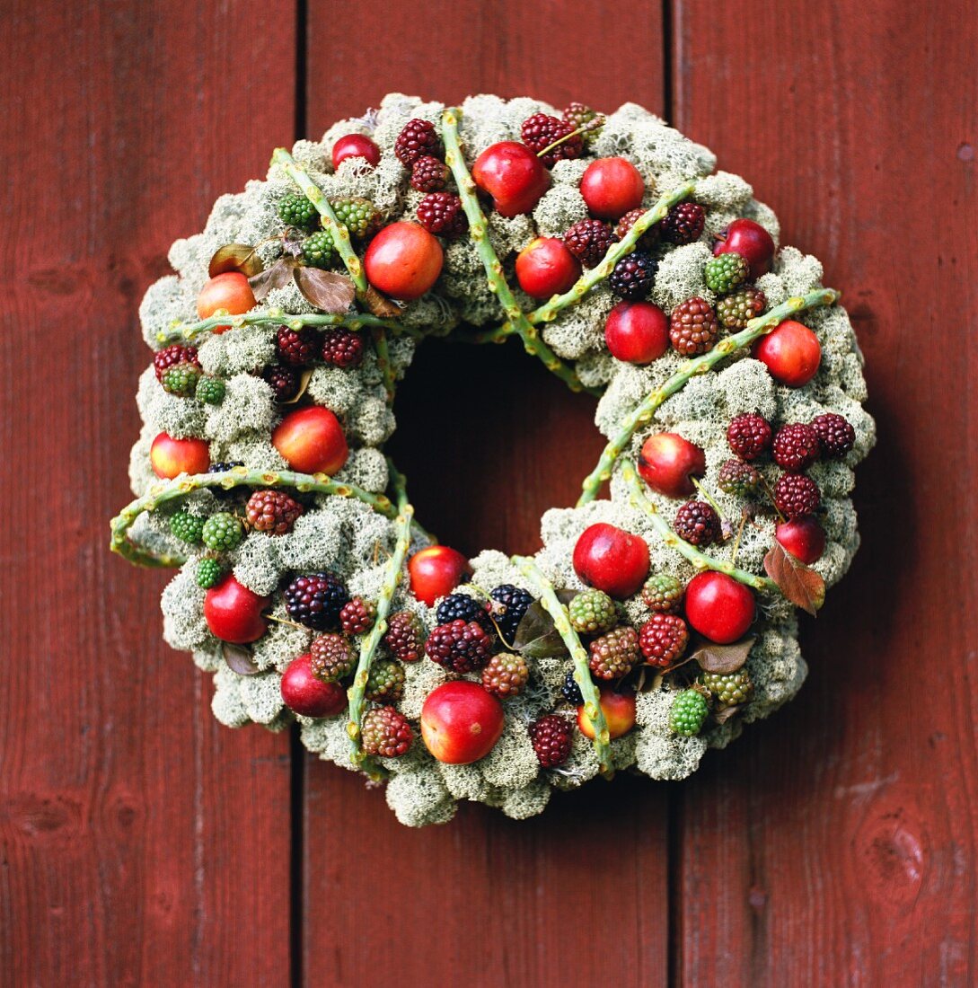 Decorative wreath with red fruit on a russet colored wooden wall
