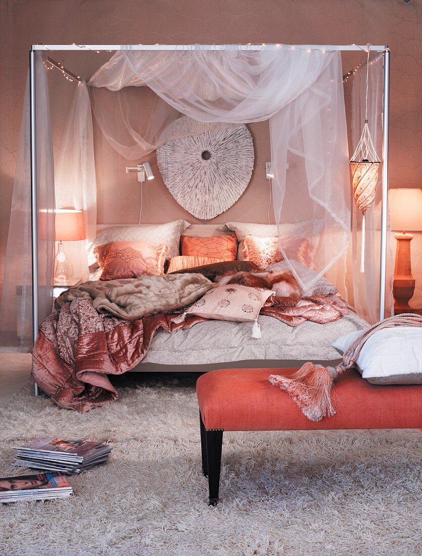 Four poster bed with a canopy of shear fabric in a mauve bedroom