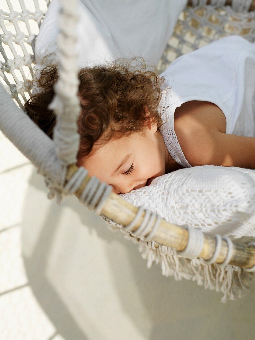 Child snuggling with pillows in a hammock