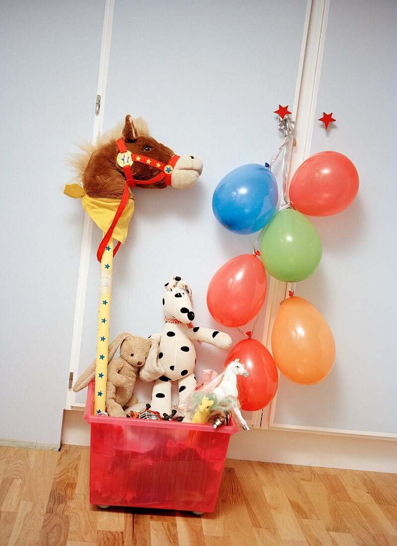 Spielkiste mit Stofftieren und aufgeblasenen Luftballons