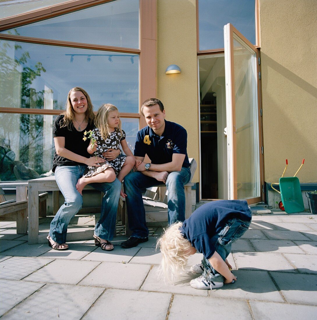 Junge Familie auf Terrasse vor modernen Haus