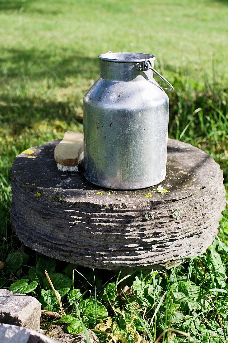 Milk can and brush on a stone