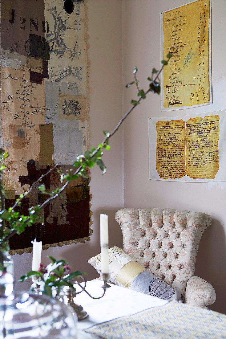 Flowering twigs and candlesticks on table in front of light reading chair in corner of living room