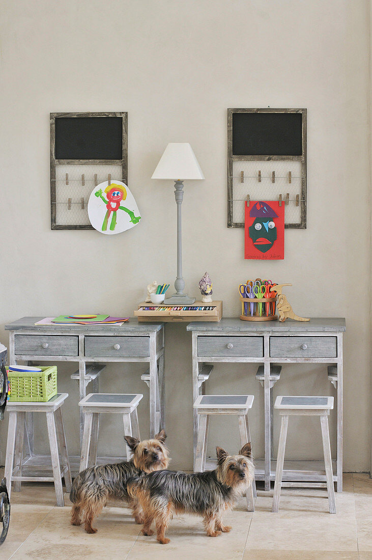 Kleine Hunde im Kinderzimmer mit rustikalen Schreibtischplätzen und Hockern