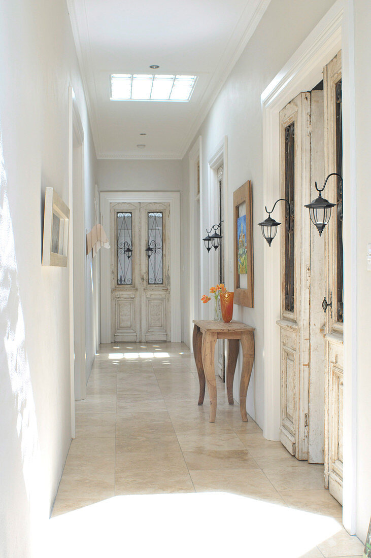 Schmaler Korridor im traditionellen Landhaus mit Glaseinsätzen in Türen und rustikalem Wandtisch