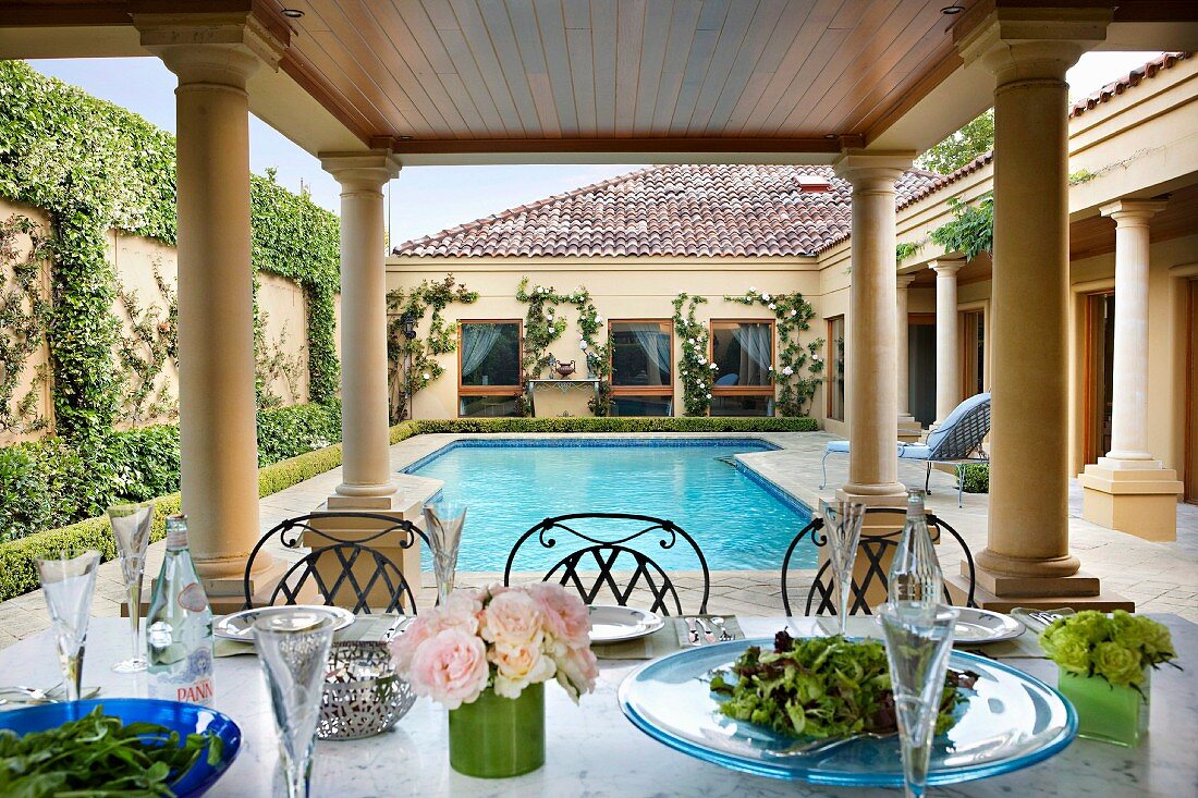 Gedeckter Tisch auf Terrasse mit Säulen und Pool im herrschaftlichen Anwesen