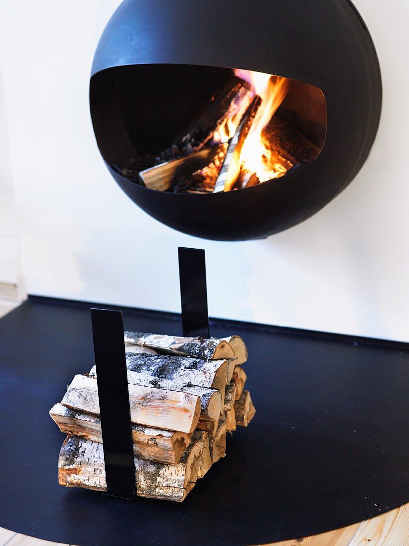Hanging fireplace with blazing fire swinging above a pile of wood